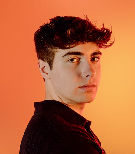 Alban MINANA, cofondateur de l'agence de communication Studio Kyne. Homme regard de côté sur fond dégradé orange