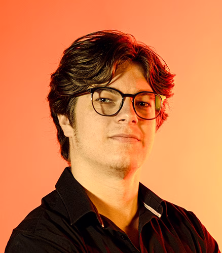 Nolan LUZET, cofondateur de l'agence de communication Studio Kyne. Homme portant lunettes regard face fond dégradé orange